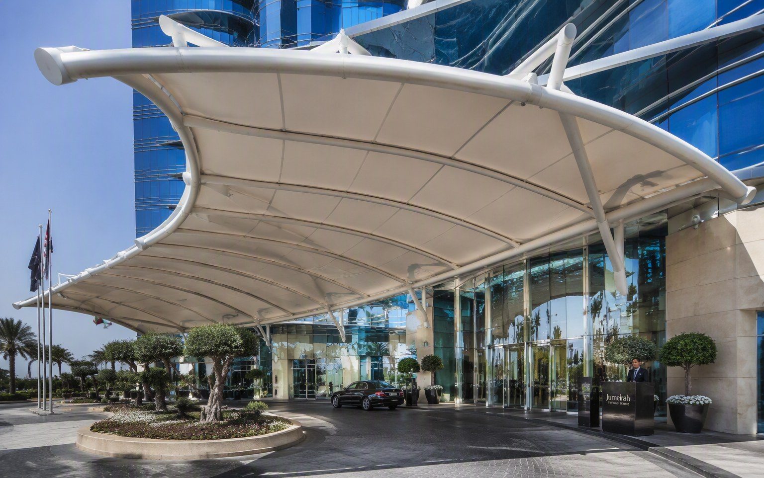 Curved entrance canopy over a hotel drop-off area in Dubai by Al Hamra Industries