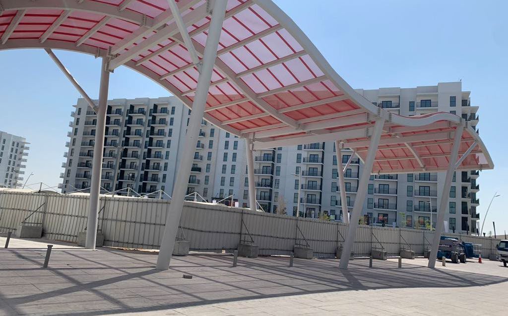 Curved red canopy structures at the Water’s Edge community, Yas Island
